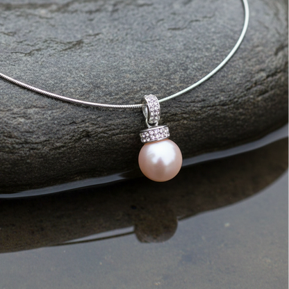 other of pearl parelketting met zalm kleurige parel en stras steentjes close up liggend op steen | Zalamie