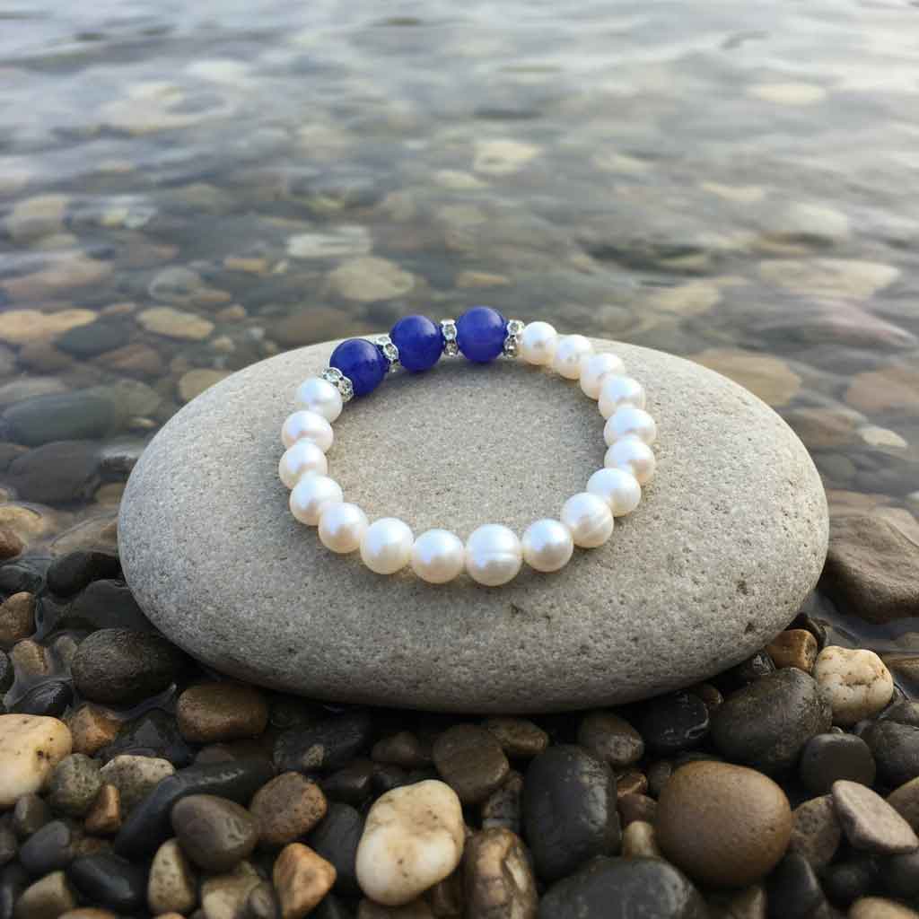 Wit zoetwater parel armband met blauwe jade en stras steentjes liggend op steen achteraanzicht, elastisch | Pearl Blue Jade