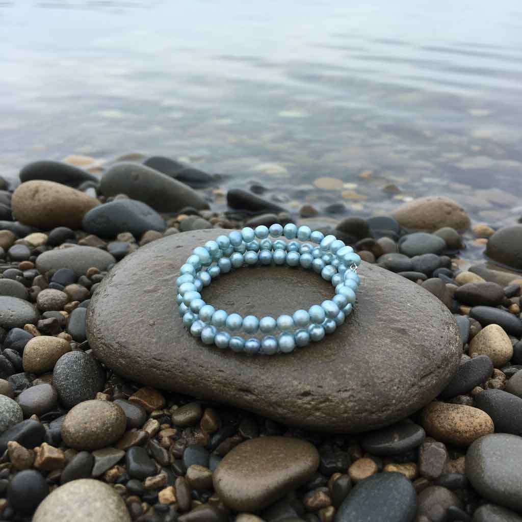 Zoetwater parel wikkel armband met aqua blauwe parels liggend op steen bij water | Zen Aqu