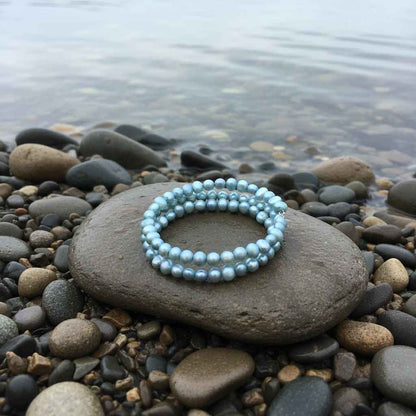 Zoetwater parel wikkel armband met aqua blauwe parels liggend op steen bij water | Zen Aqu