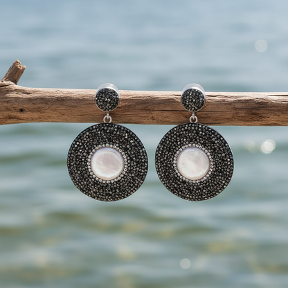 Zoetwater parel oorbellen aan tak met waterachtergrond