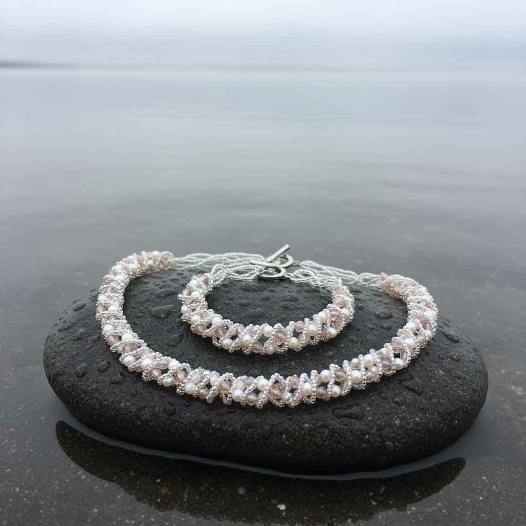 Witte zoetwater parel set bestaande uit een parelketting en parel armband met beige glaskristallen liggend op natte steen| set Pearl Crystal Clear