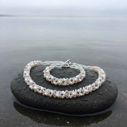 Witte zoetwater parel set bestaande uit een parelketting en parel armband met beige glaskristallen liggend op natte steen| set Pearl Crystal Clear