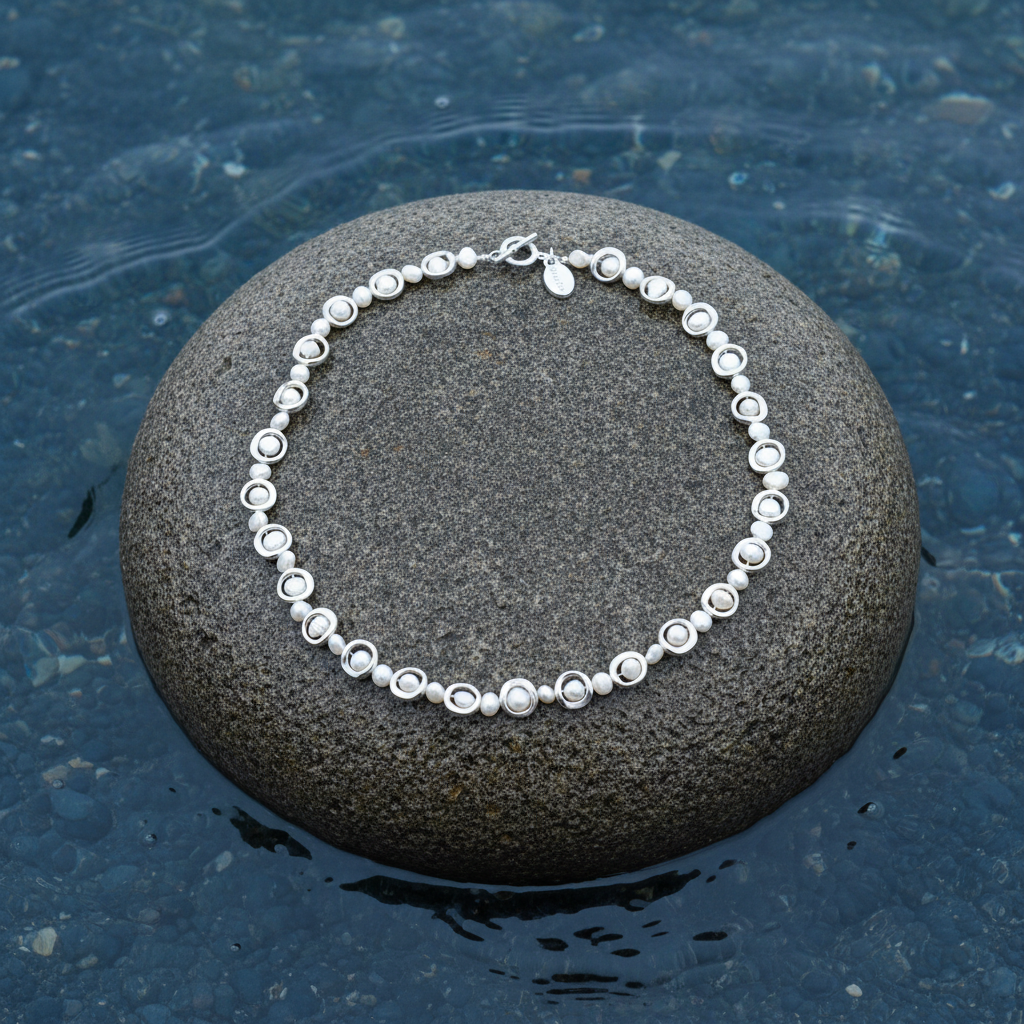 Zoetwater parelketting Pearl Geometric op steen blauwe waterrand bewolkte dag