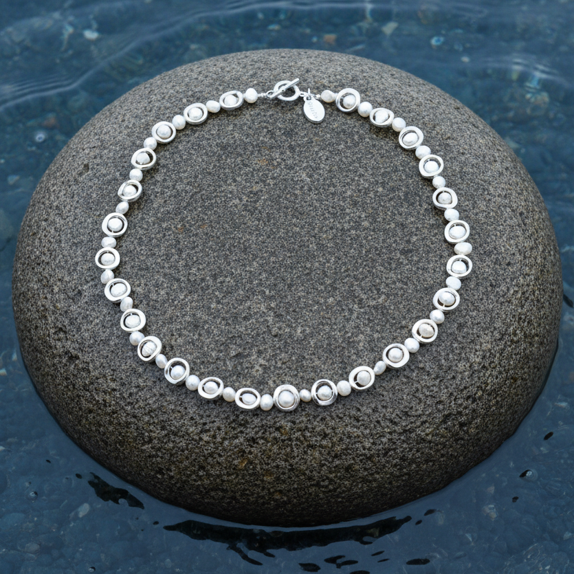 Zoetwater parelketting Pearl Geometric op steen blauwe waterrand bewolkte dag