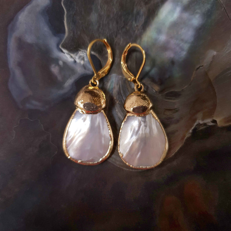 Witte parelmoeren oorbellen met goud edelstaal liggend in schelp