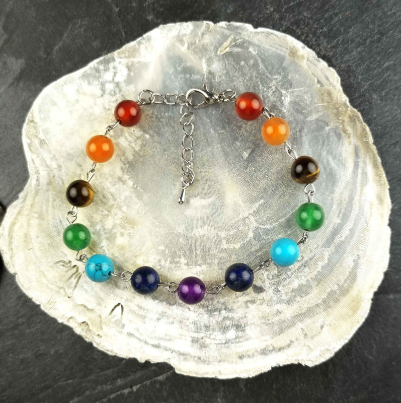 Edelstenen armband met veel gekleurde edelstenen| regenboog armband | Chakra armband liggend op witte schelp | Gemma