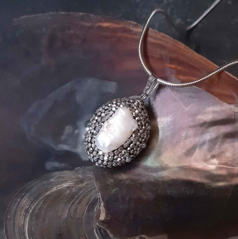 Detail van zoetwater parelketting met witte parel hanger met stras steentjes en zilver edelstaal liggend in schelp | Bright Biwa Silver