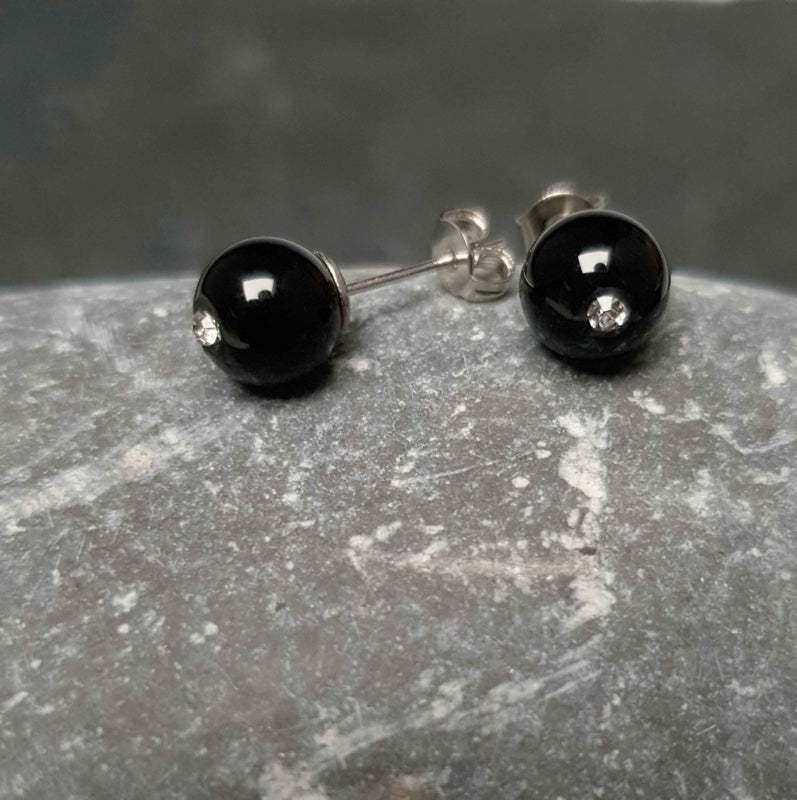 Zwarte edelstenen oorbellen met agaat en stras steentje, liggend op kei vooraanzicht | Bling Black Agate
