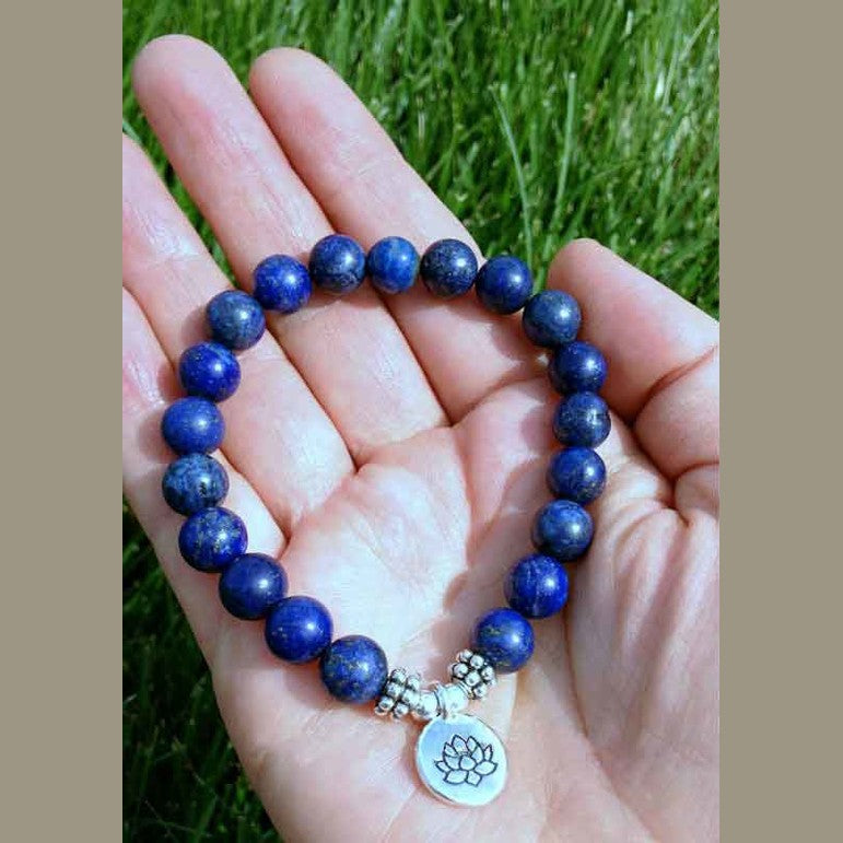 Blauw edelstenen armband met zilver lotus bedeltje liggend in hand, elastisch edelstenen armband