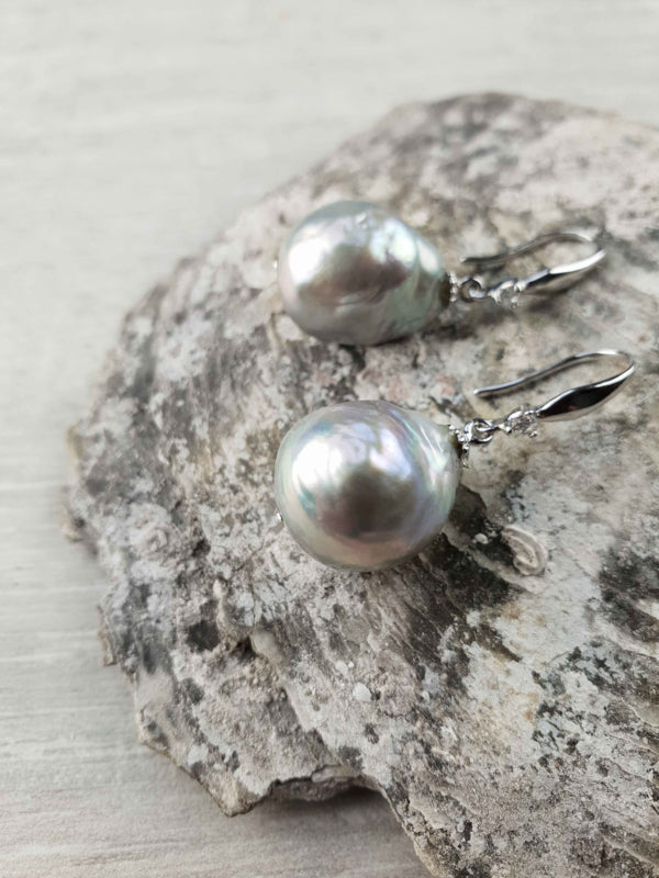 Grijze zoetwater parel oorbellen met sterling zilveren oorbelhaakjes en stras steentje liggend op steen | Bling Kasumi Grey Pearl