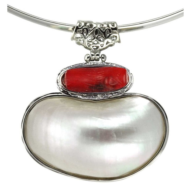 Detail van koralen ketting met wit parelmoeren hanger aan spang