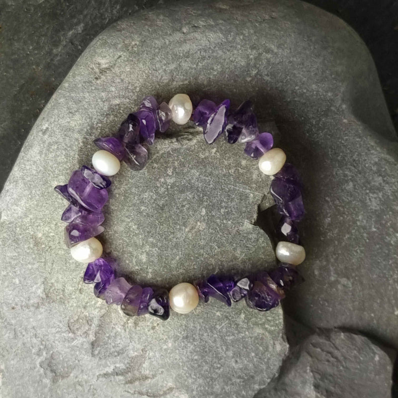 Wit zoetwater parel armband met paarse edelsteen amethist, elastisch parel armband, liggend op kei | Pearl Amethyst Chip