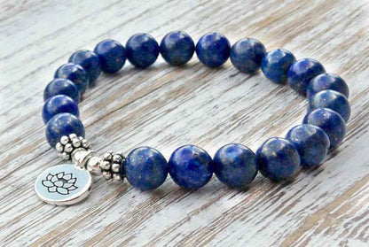 Blauw edelstenen armband met zilver lotus bedeltje, lapis lazuli armband liggend op hout