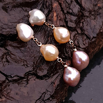 Lange zoetwater parel oorbellen met witte, zalm en roze barok parels en rosé goud hangend aan natte schors, zijaanzicht | 3 Baroque Soft Pearls