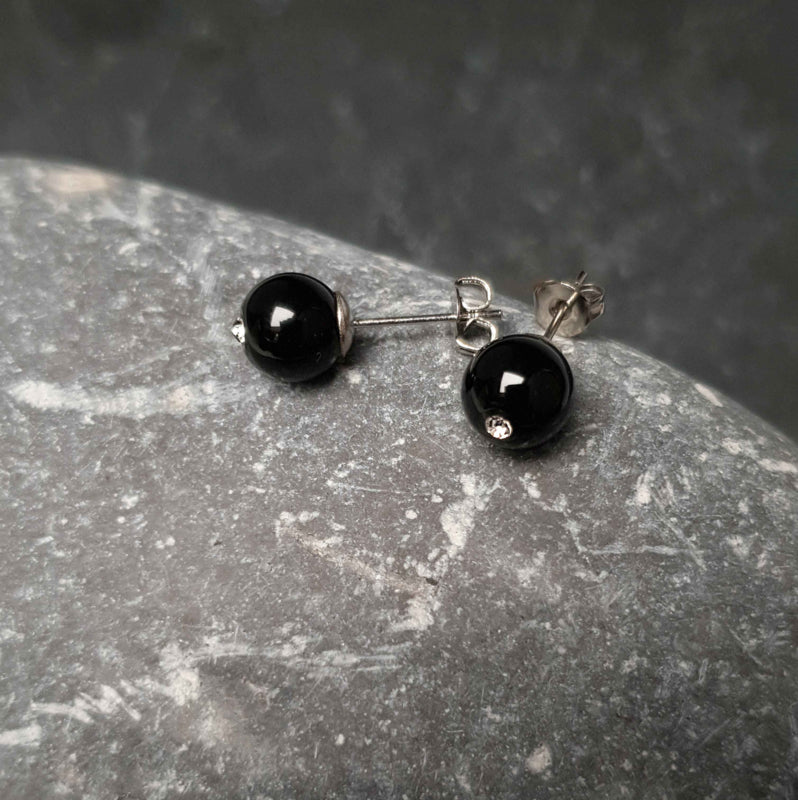 Zwarte edelstenen oorbellen met agaat en stras steentje, liggend op kei | Bling Black Agate