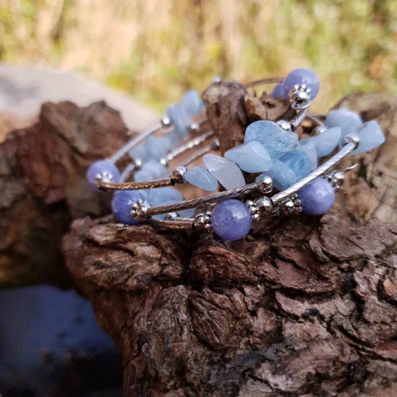 Blauw edelstenen wikkelarmband met aquamarijn en aventurien liggend op hout, zijaanzicht