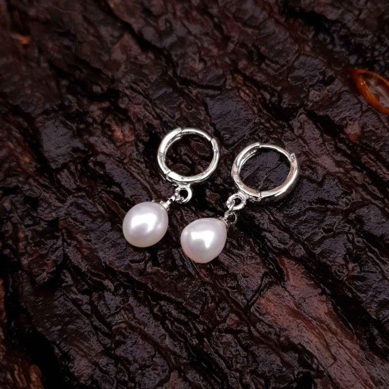 Witte zoetwater parel oorringen met witte parel en zilver edelstaal liggend op hout | Cadeau set met zoetwater parel oorbellen Bente