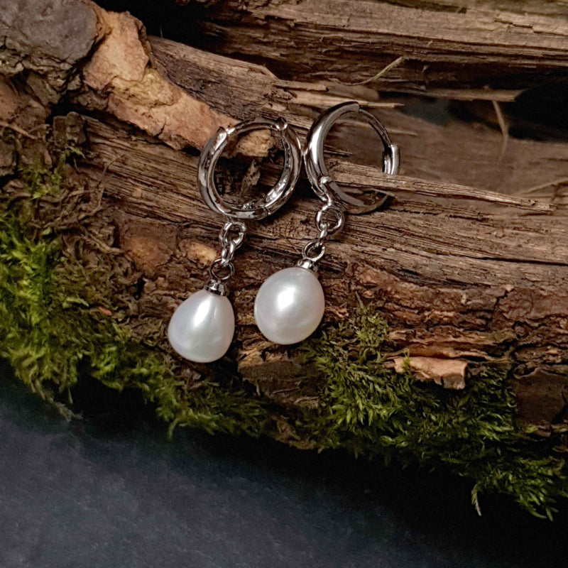 Witte zoetwater parel oorringen met witte parel en zilver edelstaal liggen op hout | Cadeau set met zoetwater parel oorbellen Bente