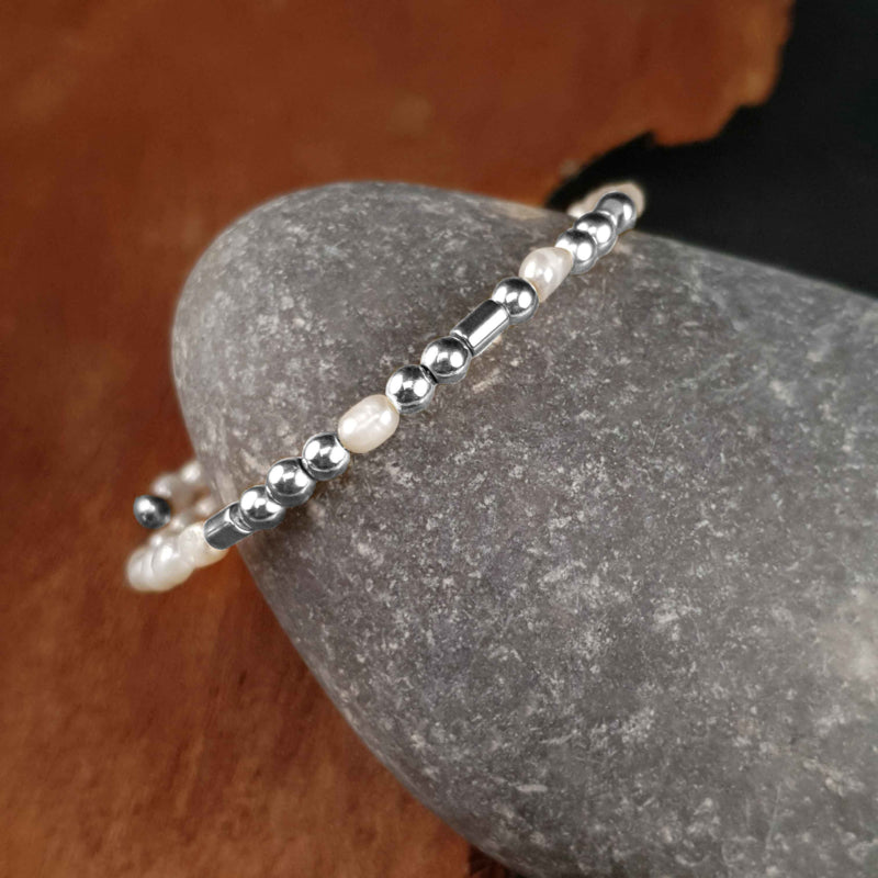 Wit zoetwater parel wikkelarmband met edelsteen zilver hematiet liggend tegen kei | Cadeau set zoetwater parel armband Morse Code BFF Pearl Silver