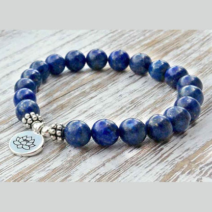 Blauw edelstenen armband met zilver lotus bedeltje, lapis lazuli armband liggend op hout