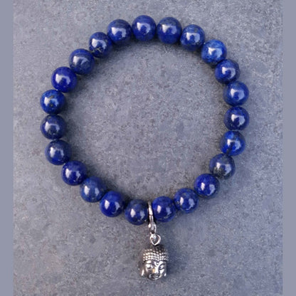 Blauw edelstenen armband met lapis lazuli en boeddha bedeltje liggend op leisteen | Lapis Lazuli Silver Dangling Buddha Head