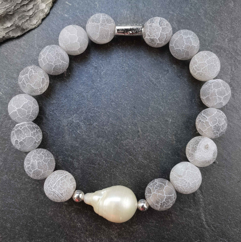 Zoetwater parel armband met witte parel en grijze edelsteen agaat, elastisch liggend op leisteen| Frozen Grey Agate White Pearl