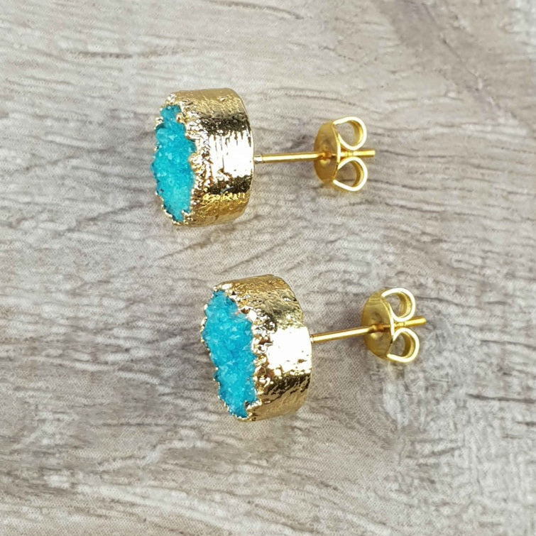 Edelstenen oorknoppen met aqua blauwe druzy agaat en goud liggend op hout | Druzy Gold Deep Sky Blue