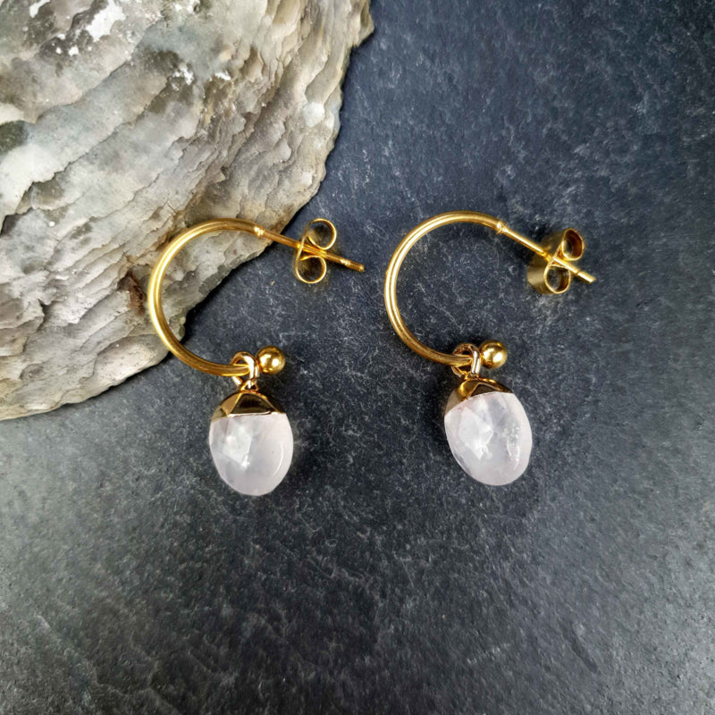 Witte edelstenen oorringen met bergkristal en goud edelstaal liggend op steen | Golden Hope 15 mm Clear Crystal