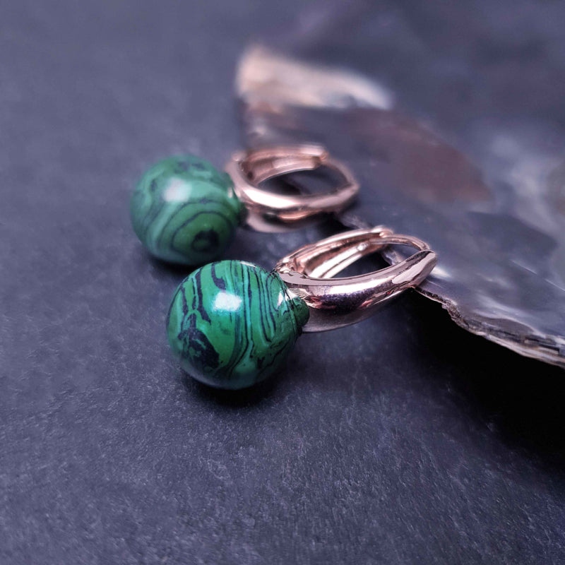 Groene edelstenen oorbellen met malachiet en rose goud liggend tegen schelprand | Rose Gold Malachite Ball