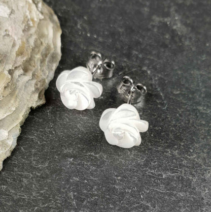 Witte parelmoeren oorknopjes in bloem vorm liggend op leisteen | White Shell Flower 8 mm