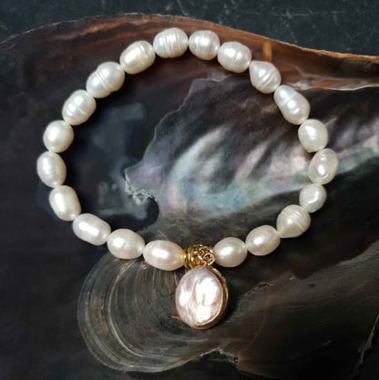 Wit zoetwater parel armband met rond bedeltje liggend in schelp | Golden Pearl Coin