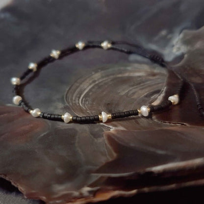 Wit zoetwater parel schuif armband met zwarte en gouden kraaltjes liggend in schelp | Mini Pearl Bead Black
