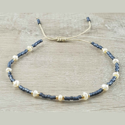 Wit zoetwater parel armband met blauwe en gouden kraaltjes en schuifsluiting liggend op hout | Mini Pearl Bead Pursian Blue