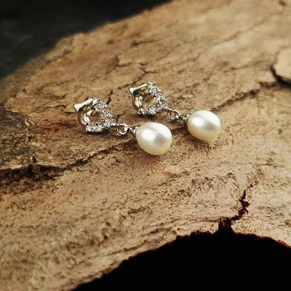 Witte zoetwater parel oorbellen met stras steentjes liggend op hout | Bling Pearl Heart W