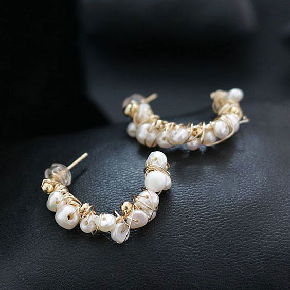 Oorringen met witte parels en goud draad liggend op zwart leer | Goa