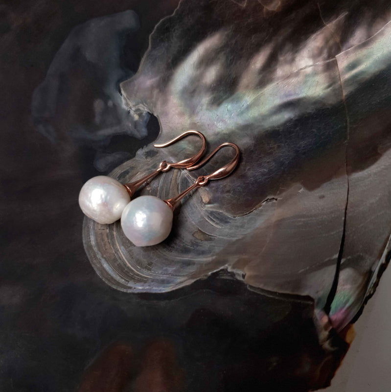 Lange witte zoetwater parel oorbellen met rose goud kleur, zijaanzicht liggend in schelp | Kasumi White Rose Gold