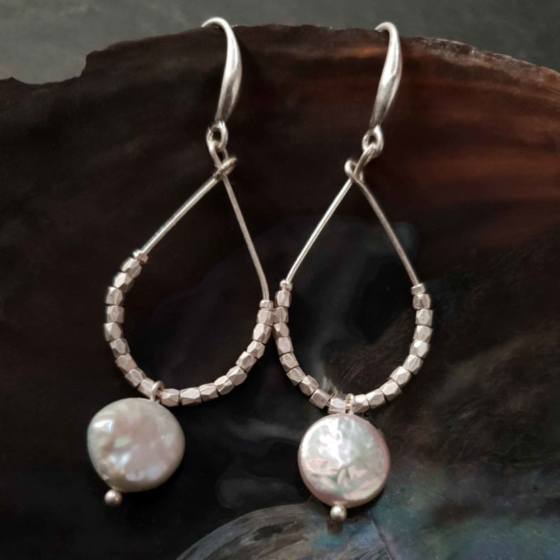 Lange witte zoetwater parel oorbellen met witte coin parel en mat zilver hangend in schelp | Milany Silver