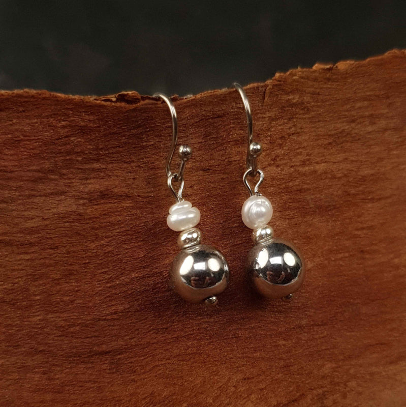 witte zoetwater parel oorbellen met zilveren edelsteen hematiet en zilver edelstaal met achtergrond schors | Bold Silver Pearl Hematite