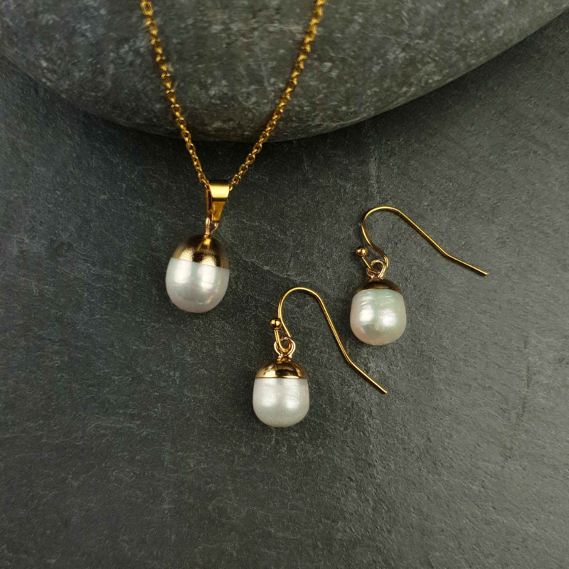 Witte zoetwater parel set bestaande uit witte parelketting en parel oorbellen met goud edelstaal en parel hanger liggend op steen | set Gold Dip White Pearl
