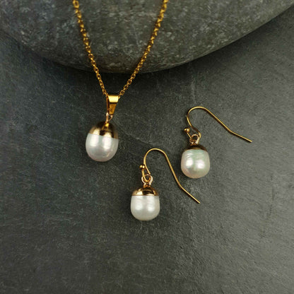 Witte zoetwater parel set bestaande uit witte parelketting en parel oorbellen met goud edelstaal en parel hanger liggend op steen | set Gold Dip White Pearl