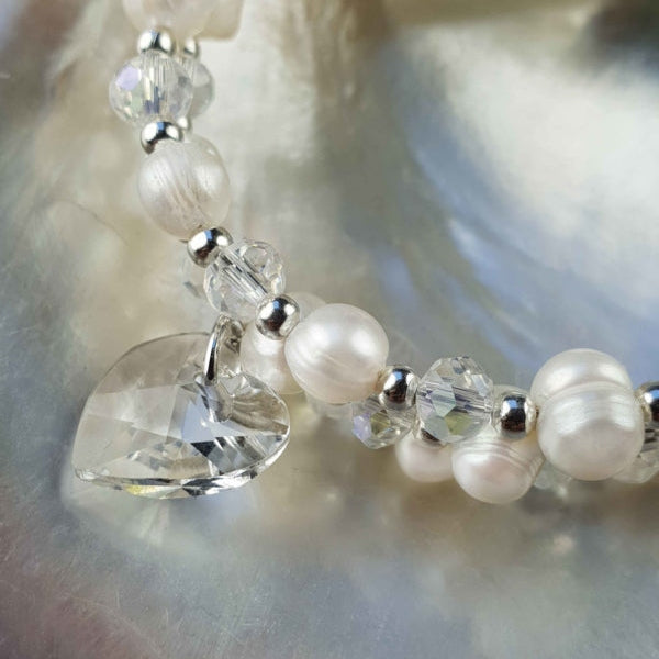 Detail van wit zoetwater parel wikkel armband met kristallen hartje liggend in schelp | Wrap Pearl Crystal Heart
