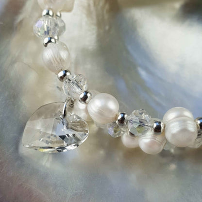 Detail van wit zoetwater parel wikkel armband met kristallen hartje liggend in schelp | Wrap Pearl Crystal Heart
