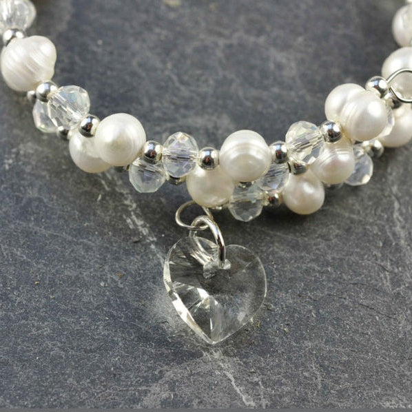 Detail van wit zoetwater parel wikkel armband met kristallen hartje liggend op leisteen | Wrap Pearl Crystal Heart