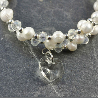 Detail van wit zoetwater parel wikkel armband met kristallen hartje liggend op leisteen | Wrap Pearl Crystal Heart