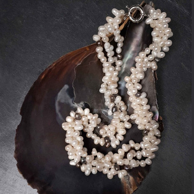 Zoetwater parelketting met witte en zwart blauwe parels in 3 strengen liggend in schelp | Amira