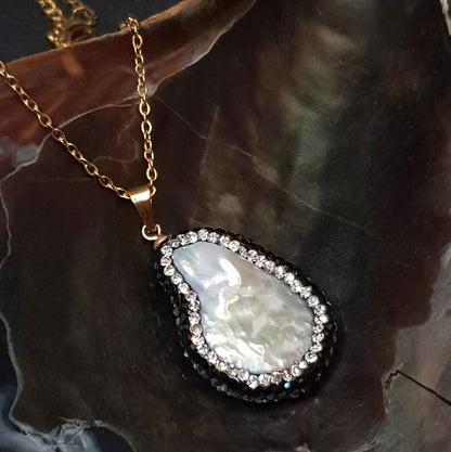 Detail van zoetwater parelketting met witte parelhanger met zilveren en zwarte stras steentjes en goud edelstaal liggend in schelp | Bright Minimal Gold Teardrop