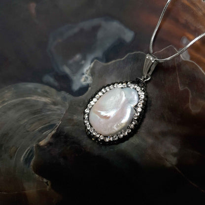Detail van zoetwater parelketting met witte parel hanger met stras steentjes en zilver edelstaal liggend in schelp | Bright Minimal Silver Teardrop