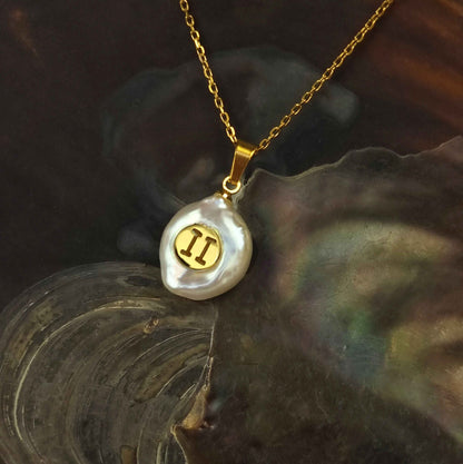 Witte zoetwater parelketting met hanger en symbool van sterrenbeeld Tweeling en goud edelstaal liggend in schelp | Gouden Sterrenbeeld Tweeling