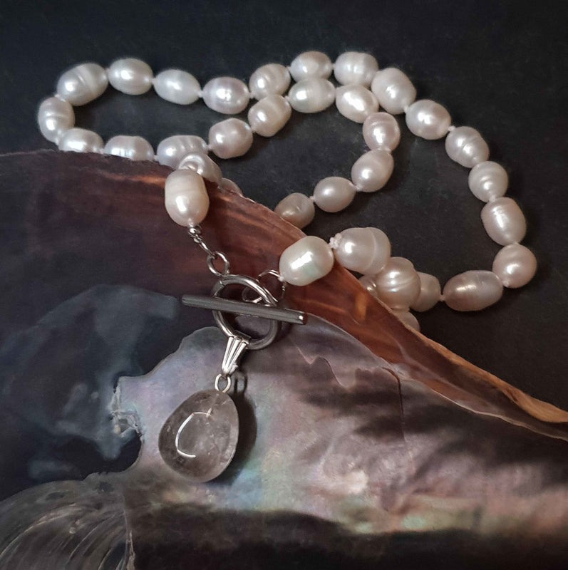 Handgeknoopte zoetwater parelketting met witte parels, zilver edelstaal en rook kwarts hanger liggend in schelp | Toggle Pearl Smokey Quartz